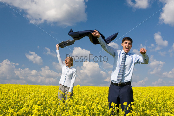 Portrait of happy business partners enjoying life and freedom in yellow field