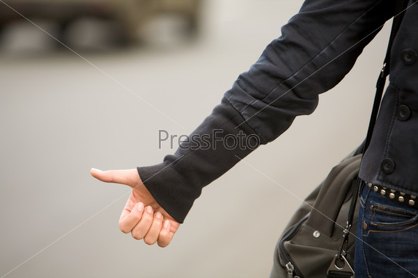 Close-up of female hand gesture of hitchhiking outside