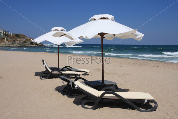 Beach umbrellas and beds facing about tides. Bulgaria, Black Sea.