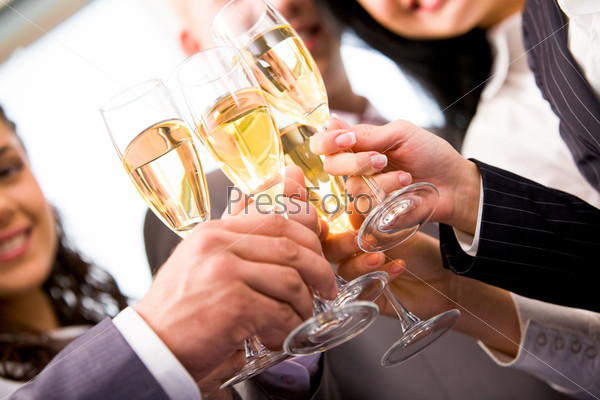 Close-up of friends hands holding glasses with champagne and making cheers