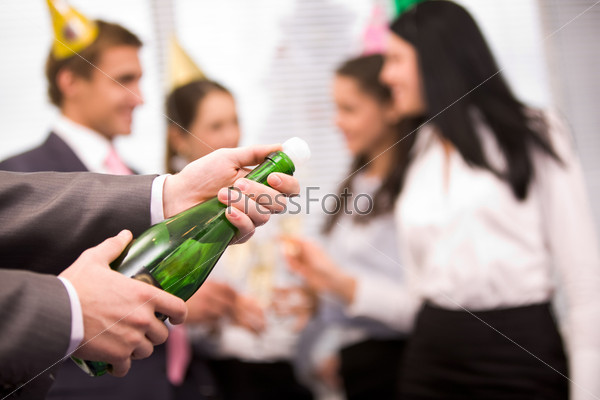 Image of male hands holding bottle of champagne and uncorking it