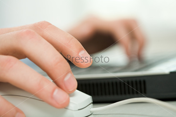 Close-up of human hand on white mouse during computer work
