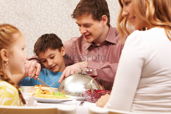 Image of handsome man showing how to cut roasted turkey to his son