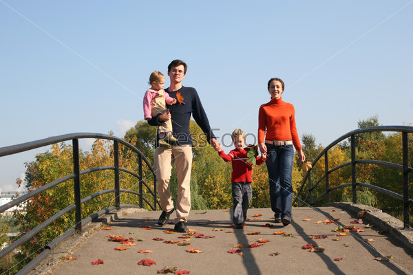 Родители с детьми идут по мосту