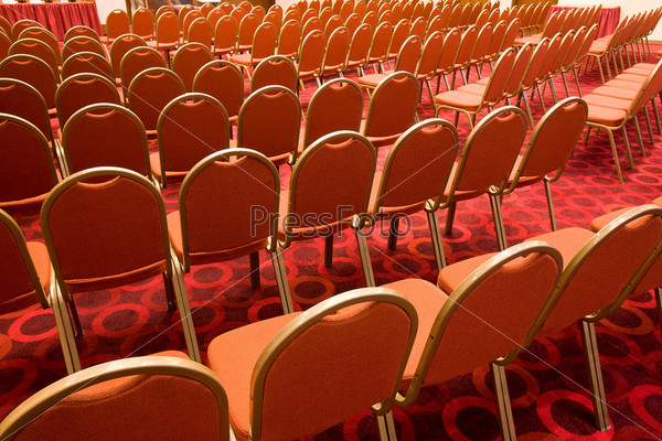 Back view of several rows of red armchairs in conference hall