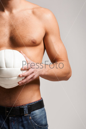 Photo of shirtless man in jeans holding volley ball in hands