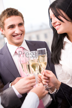Photo of happy man and woman holding flutes with champagne and smiling while toasting at party, stock photo