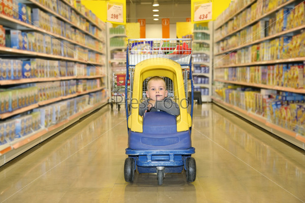 Boy in the toy automobile in the supermarket