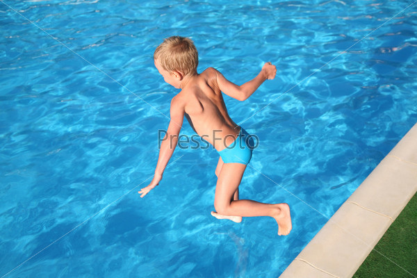 The boy jumps in pool.