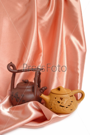 Two chinese teapots on a beige satin background