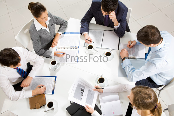 Above view of business team sitting around table and working with papers