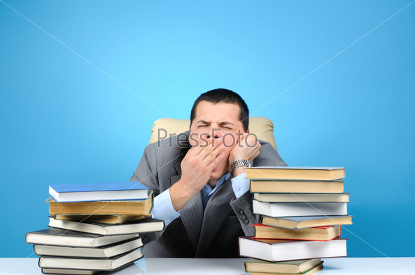 Tired businessman in the books on blue background