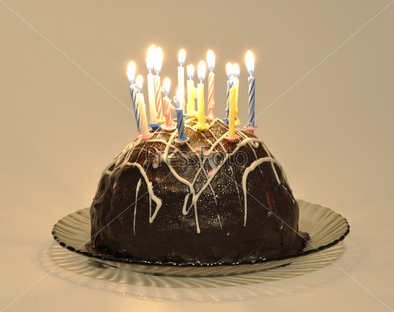Chocolate cake with candles on a cake plate on a white background, stock photo