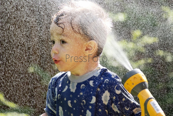 Young boy spraying a hose, summer scenic, stock photo
