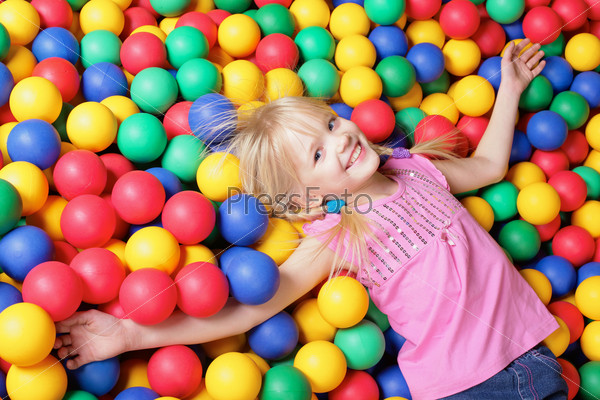 Happy girl lying on colorful balls and looking at camera