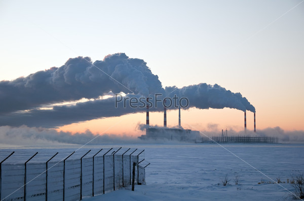 Thermal power station and smoke plume on a sunset the winter sky background