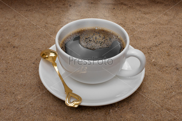 White coffee cup on sand