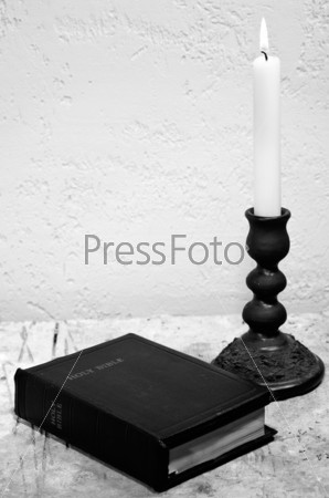 Holy Bible on the desk with burning candle
