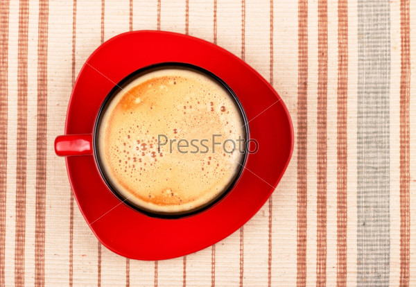 Red coffee cup on striped tablecloth top view, stock photo