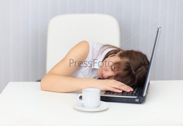Woman tired and fell asleep at table with a laptop