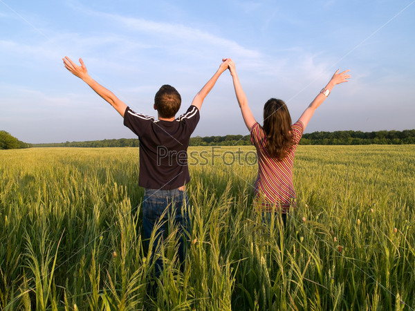 Young Couple in Field Holding Hands Up Rear View