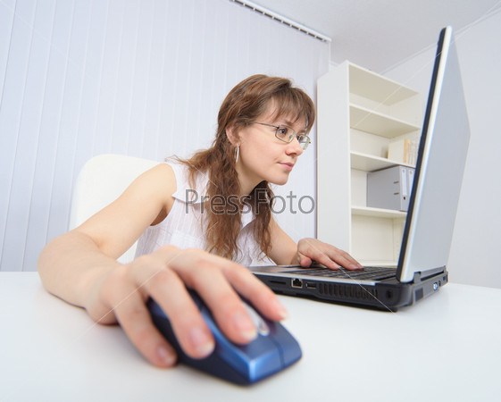 The amusing woman attentively studies the Internet by means of the laptop