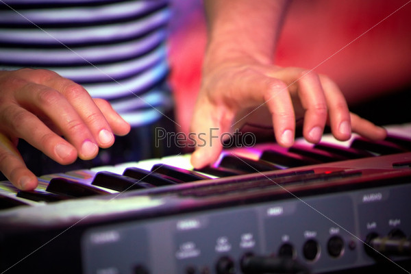 The man playing on piano in the light of scenic illumination