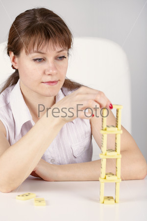 Young woman builds a precarious tower of dominoes