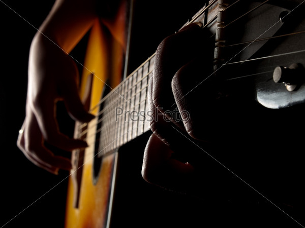 Female hands playing acoustic guitar on black background