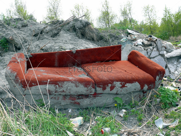 Old red sofa in the dump
