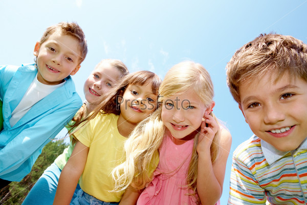 Portrait of smiling children looking at camera on background of blue sky
