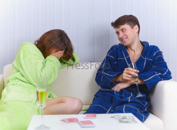 The woman has lost in cards to the man and cries, stock photo