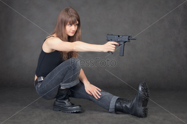 The young woman shoots from a pistol sitting on one leg