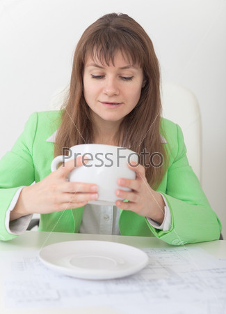 Woman looks in huge cup for coffee