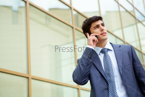 Portrait of confident businessman communicating by cellular phone outdoors