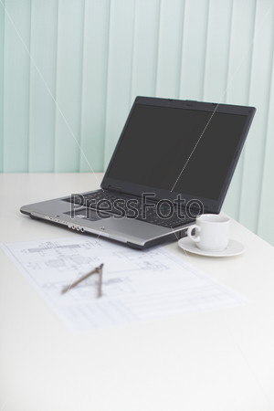 The laptop on a table with the drawing and a compasses - business a still-life