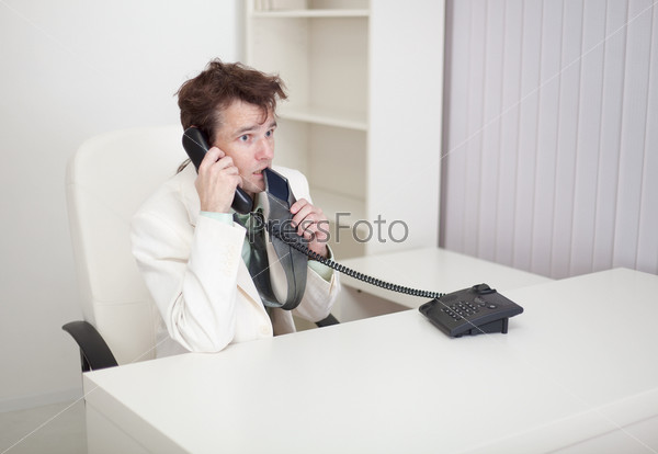 The businessman speaks on the phone, worries and eats the tie