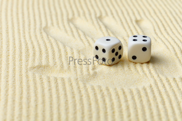 Dices on a sand surface and a palm print - an abstract art composition in yellow tones
