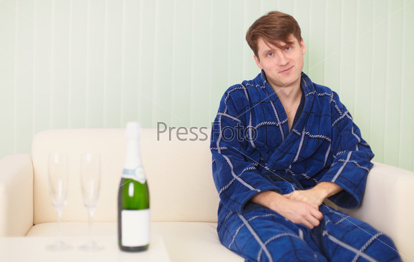 The guy in expectation of the woman with sparkling wine on a sofa