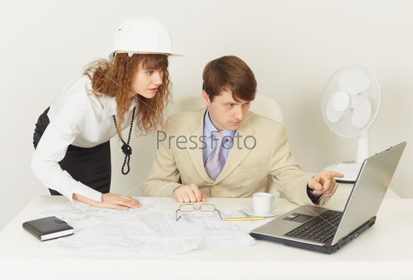 Two young engineers work over the project on the laptop