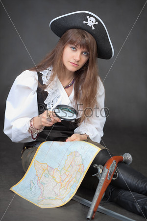 The young woman - the pirate with a sea map and a magnifier glass