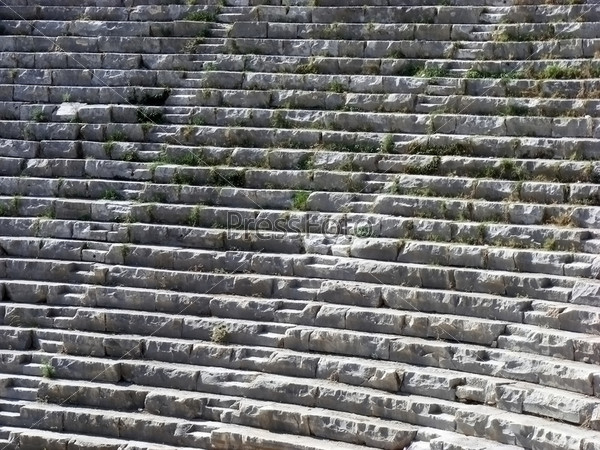 The ancient amphitheater with neat rows of stone seats and passages for the audience
