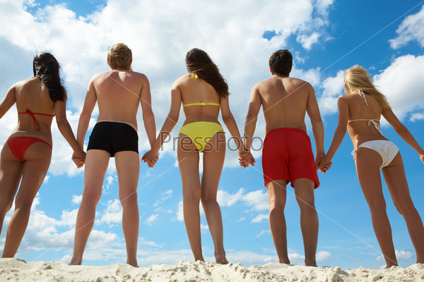 Rear view of people holding by hands at summer