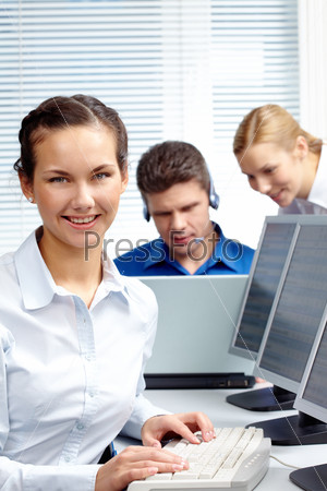 Portrait of pretty secretary sitting at workplace with computer on it in a working environment
