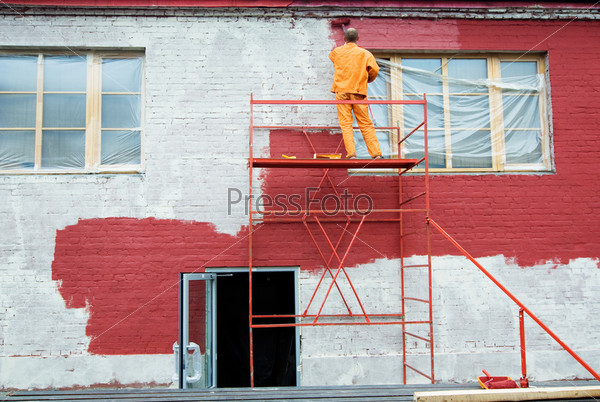 Man painting a brick wall in red