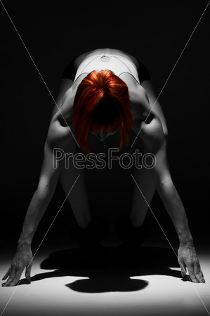 Powerful female athlete standing in the spotlight on black, stock photo