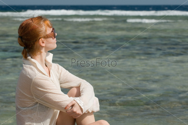 Beautiful red woman taking sun baths by the ocean