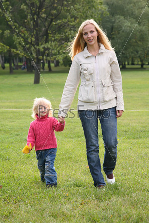 mother and daughter walk on the grass