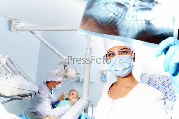 Portrait of assistant looking at patient’ x-ray photography during dental examination, stock photo