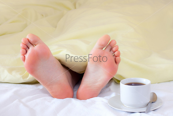 A couple of tiny feet the blanket - and cup of coffee - good morning